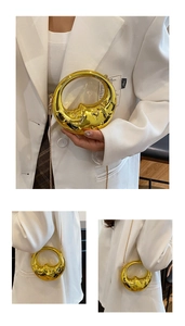 Detailed view of creative gold moon-shaped evening bag with embossed closed-eye face design