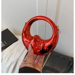 Close-up of red metallic crescent moon handbag with gold chain strap and mirror finish
