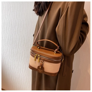Dettaglio borsa a cilindro in pelle marrone e tela beige con doppia cerniera lampo