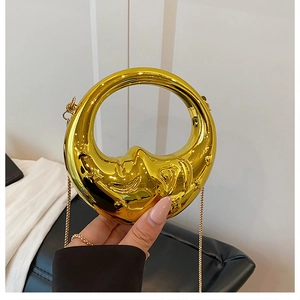 Detailed relief of an artistic moon-face on a shiny gold metallic evening handbag