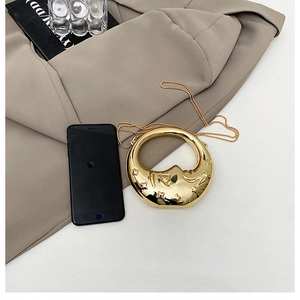 Detailed view of mini golden moon-shaped evening bag with star texture and chain strap