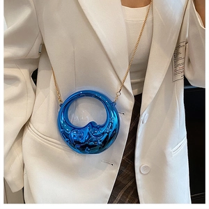 Detail of a bright blue moon-shaped mini evening bag with a gold metal chain strap