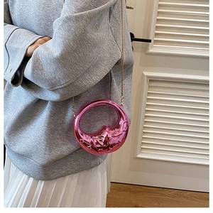 Detail view of pink metallic crescent bag with embossed texture and gold chain strap