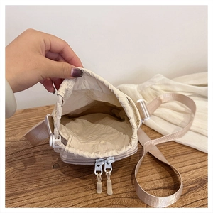 Detail of light beige nylon crossbody bag with drawstring closure and dual zip pockets