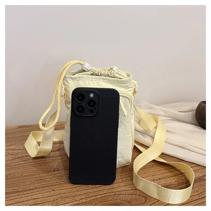 Detail view of yellow nylon drawstring crossbody bag next to a smartphone for size scale