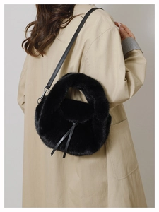 Detail of black faux fur handbag featuring elegant drawstring bow and leather strap