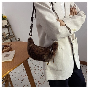Détail du sac hobo en peluche léopard avec bandoulière en cuir nouée sur un blazer