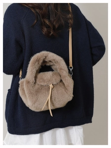 Detailed view of plush brown faux fur handbag with leather strap on a blue sweater