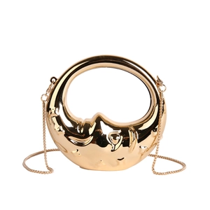 Detail of gold metal mini evening bag with moon face relief and round handle
