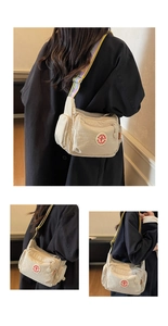 Detail view of beige multi-pocket nylon crossbody bag with colorful logo strap