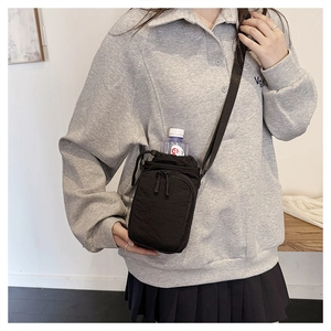 Detail of black nylon crossbody water bottle bag with front zipper pocket and strap