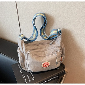 Close-up of grey nylon crossbody bag with adjustable floral strap and multiple zipper pockets