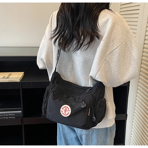 Model wearing a black multi-pocket nylon crossbody bag with adjustable wide strap