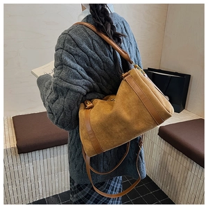 Détail du sac Boston en daim marron avec finitions en cuir et bandoulière réglable