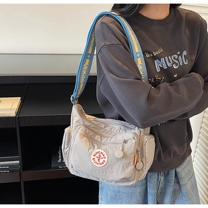 Detail of light gray nylon crossbody bag with multi-pocket and colorful woven strap