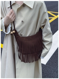 Close-up of vintage dark brown suede bucket bag with long tassels and wood bead detail
