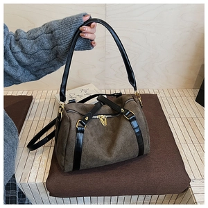 Détail du sac Boston en daim avec poignées en cuir noir et fermetures éclair dorées