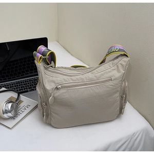Detail view of khaki crossbody bag with multi-pocket design and colorful wide strap