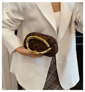 Détail de la pochette léopard en daim avec poignée dorée ronde sur une tenue moderne