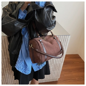 Détail d'un sac Boston en daim marron avec ferrures dorées et poignées en cuir chic