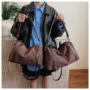 Vue détaillée du grand sac Boston en daim marron avec poignées en cuir et finitions dorées