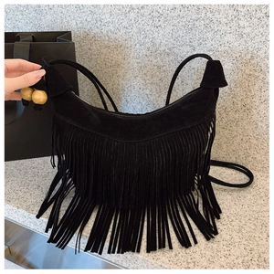Detail of black suede hobo bag with long fringes and decorative wooden beads on strap