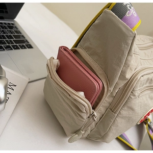 Detail of washed fabric crossbody bag featuring a side zipper pocket and colorful strap