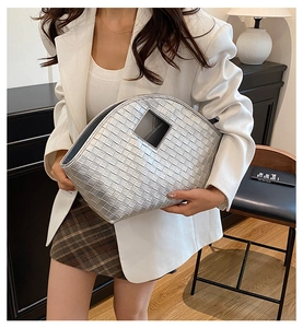 Detail of silver metallic woven tote bag with cutout handle shown in chic fashion setting