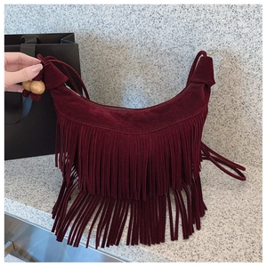 Close-up of burgundy suede tassel shoulder bag with decorative wooden beads detail