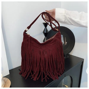 Macro detail of burgundy faux suede fringe shoulder bag with premium golden hardware