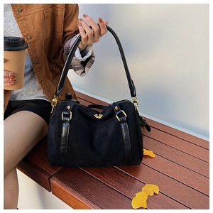 Détail d'un sac boston en daim noir avec zips dorés dans un décor extérieur automnal