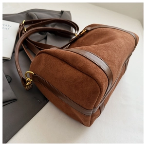 Détail du sac Boston en daim marron avec garniture en cuir sur blazer gris
