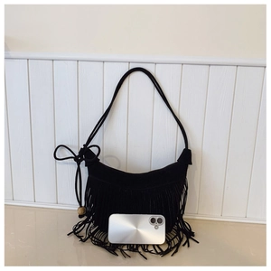 Detail view of black suede fringe shoulder bag with wooden bead and knotted tassel strap