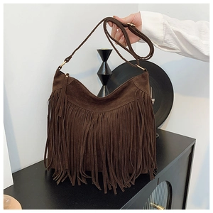 Close-up of deep brown suede tassel tote bag with bohemian fringe in a retro setting