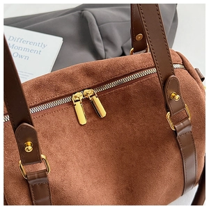 Détail macro du sac Boston en daim marron avec doubles fermetures éclair dorées de luxe