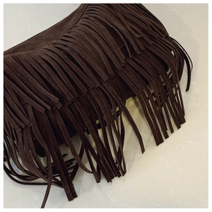 Detailed view of dark brown faux suede tassels on a bohemian style bucket shoulder bag