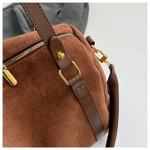 Gros plan du sac Boston en daim marron avec ferrures dorées et détails en cuir de qualité