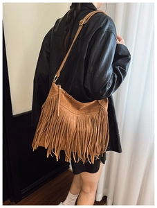 Detail of brown faux suede tassel shoulder bag showing long fringe and retro boho style