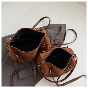 Détail de deux sacs Boston en daim marron montrant la doublure et les lanières en cuir