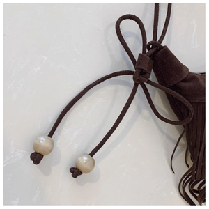 Detailed close-up of dark brown suede tassel bag with decorative beads and drawstring texture