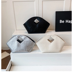 Detailed view of woven leather tote bags in black, silver, and cream on a display stand