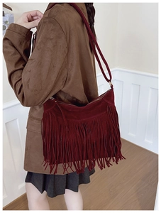 Detail of bohemian dark red suede crossbody bag with long fringes and zipper closure