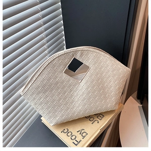 Macro detail of beige woven leather handbag showing intricate grid texture and craftsmanship