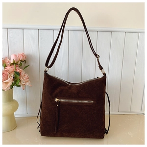 Detail of dark brown suede shoulder bag with metal zipper pocket and adjustable strap