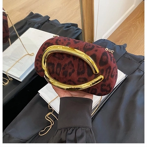 Détail d'une pochette bordeaux à motif léopard avec poignée dorée et bandoulière