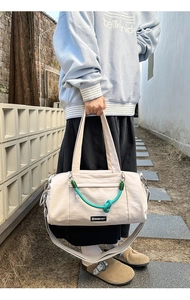Dettaglio della borsa da viaggio bianco sporco con manico verde e tracolla regolabile