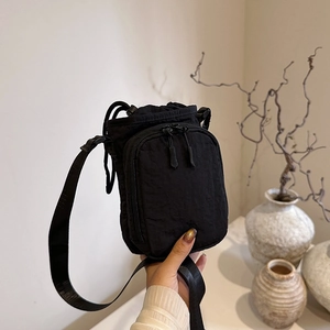 Versatile black nylon crossbody bag with drawstring closure and front pocket for outdoors