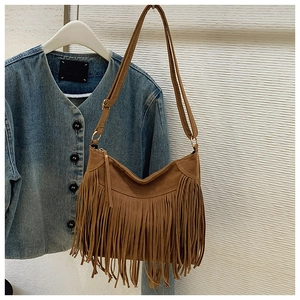 Detail of brown suede tassel shoulder bag with bohemian fringe and metallic hardware