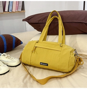 Dettaglio borsa da viaggio a cilindro in nylon giallo con tracolla e etichetta logo