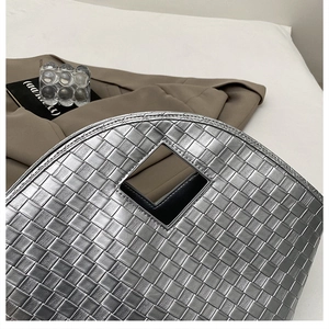 Close-up of metallic silver woven tote bag with square cutout handle and modern texture